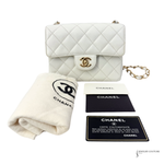 White quilted Chanel handbag with authenticity card and cloth on a white background