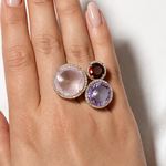 Hand wearing two rings with gemstones on a white background