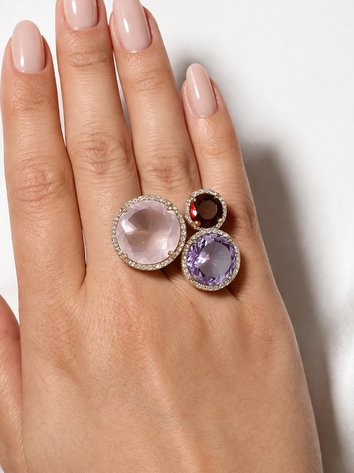 Hand wearing two rings with gemstones on a white background