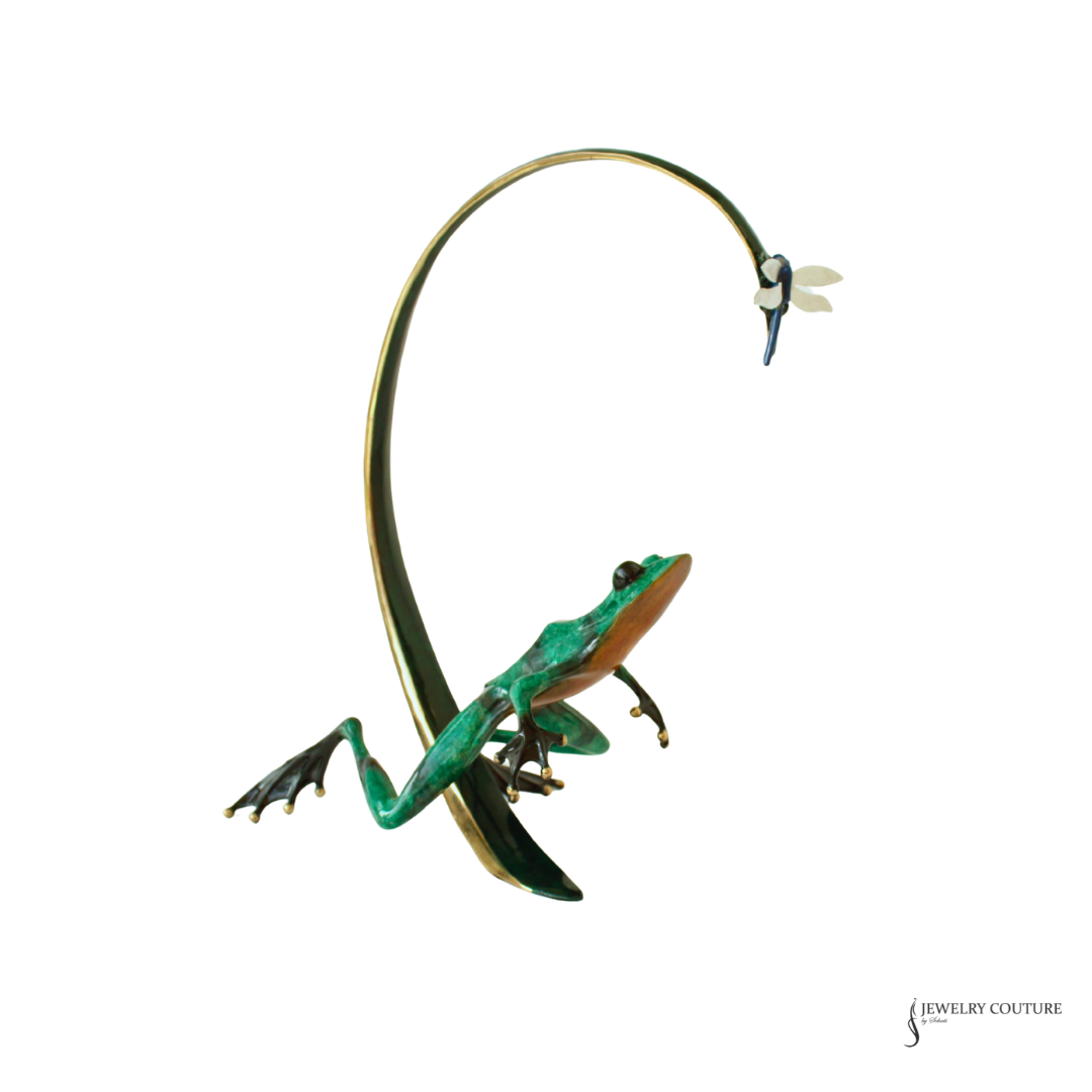 A green frog pendant brooch with gold-toned metal details, set against a plain white background.