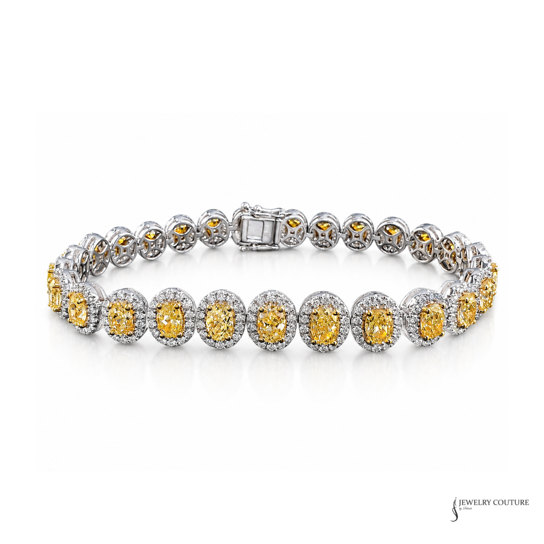 A silver tennis bracelet featuring round yellow diamond gemstones in a halo setting, displayed on a clean white background with a Jewelry Couture logo in the bottom right corner.