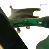 Close-up of a sculptural jewelry display piece featuring a glossy emerald green curved bar with a dark gray abstract wing-like element behind it, photographed against a white background. A small 'JEWELRY COUTURE' watermark appears in the top right.