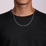 Person wearing a silver chain necklace on a plain background
