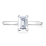 Diamond ring with emerald-cut gemstone on a white background