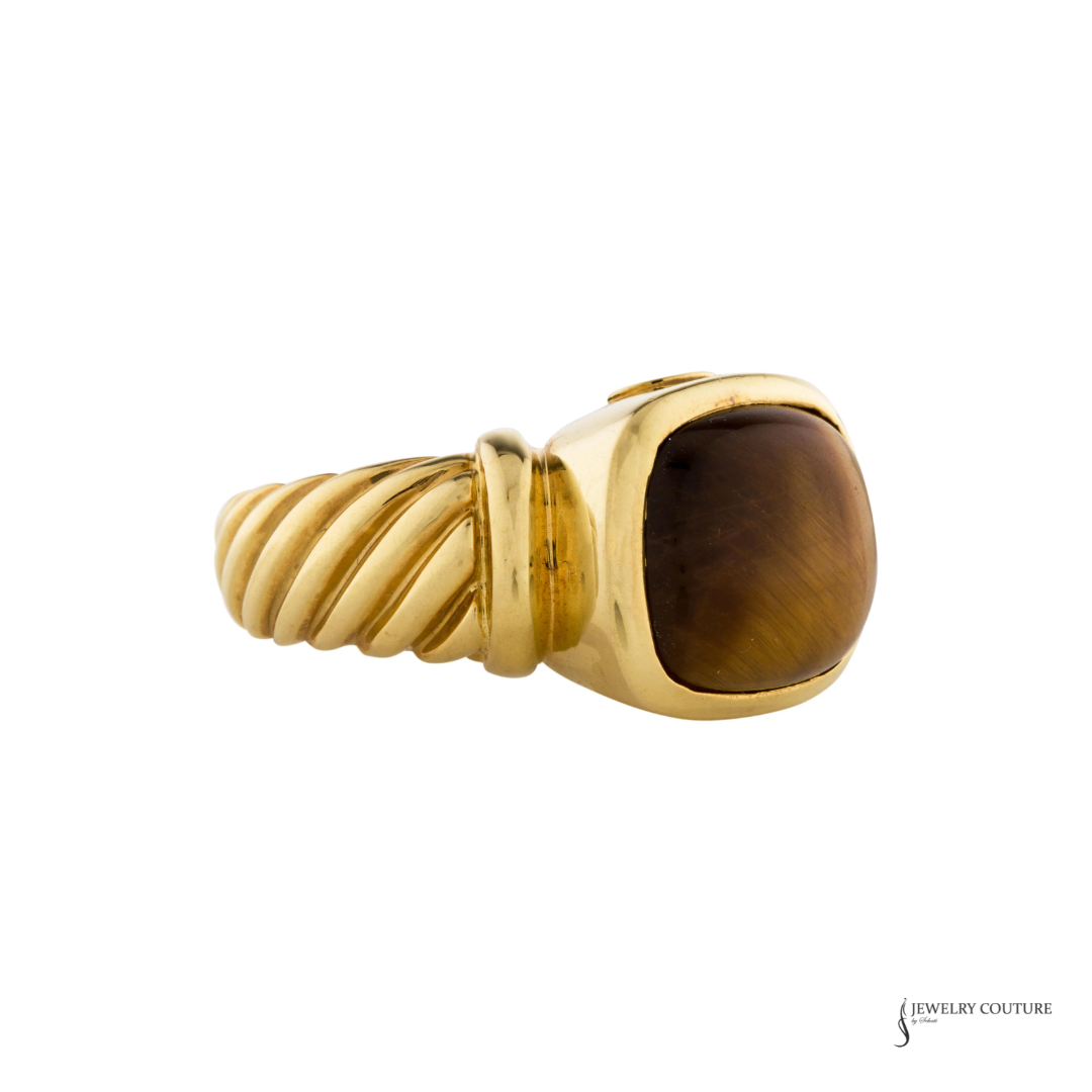 A yellow gold ring featuring a twisted rope band and a large cushion-cut brown tiger's eye stone, shown against a plain white background.