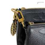 Black leather handbag with gold zipper and chain detail on a white background