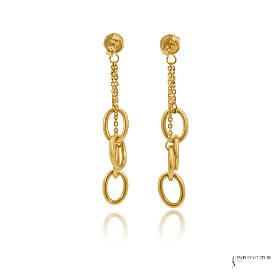 A pair of gold dangle earrings featuring a short chain, three interlocking oval links, and a larger oval drop, displayed on a clean white background with a faint reflection below.