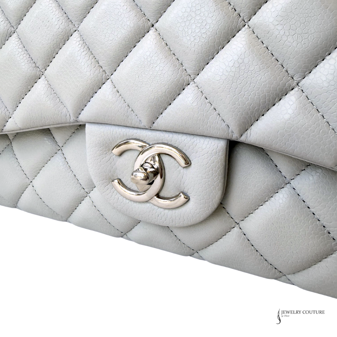 Close-up of a quilted white handbag with a gold Chanel logo on a white background.