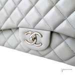 Close-up of a quilted white handbag with a gold Chanel logo on a white background.
