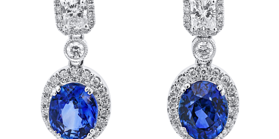 Pair of earrings with blue gemstones and diamond-like stones on a white background