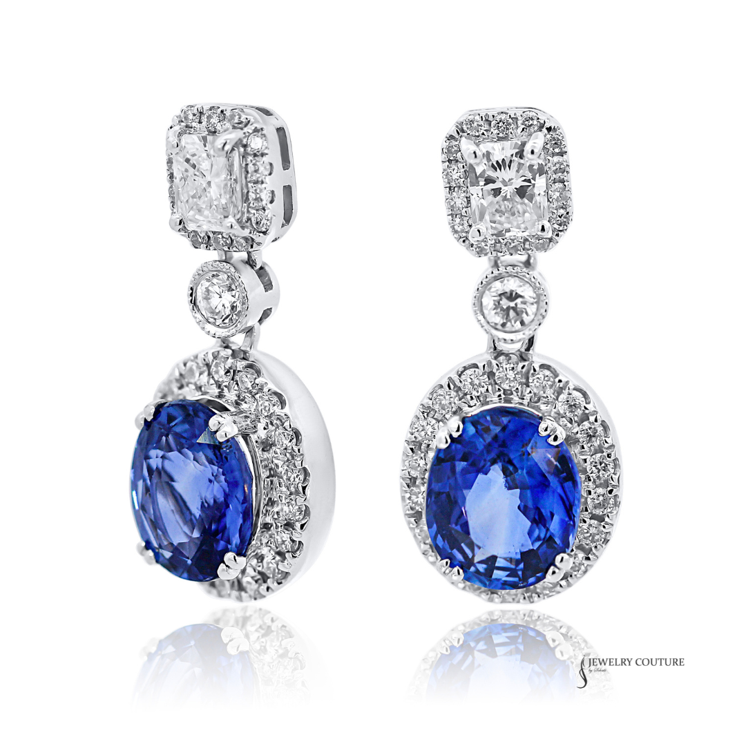 Pair of earrings with blue gemstones and diamond accents on a white background
