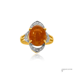 A yellow gold ring featuring a large oval cabochon orange gemstone, surrounded by a silver-toned leaf-shaped halo with small clear stones, set against a plain white background.