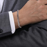 Silver chain bracelet on a person's wrist with a dark gray suit background