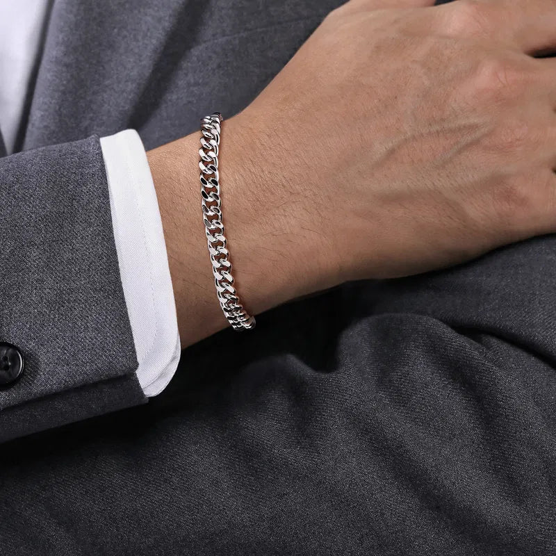 Silver chain bracelet on a person's wrist with a dark gray suit background