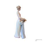 A porcelain figurine of a mother and child in profile, with the mother wearing a long white gown with a pink bodice and the child in a light blue outfit. The figurine is set against a plain white background.