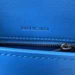 Close-up of a bright blue textured leather zippered pouch with the BALENCIAGA logo debossed on the front and a silver zipper.