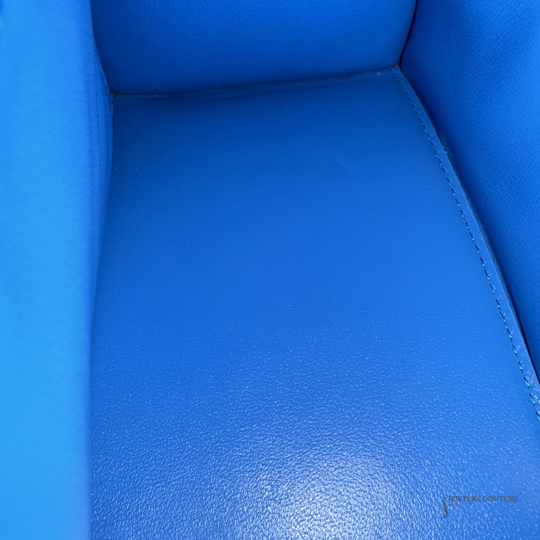Close-up of a bright blue upholstered chair or seat with a pebbled leather-like texture and visible stitching along the side.