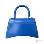 A bright blue leather handbag with a structured top handle, photographed against a plain white background.