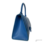A blue leather handbag shown from a side angle on a plain white background, with a small Jewelry Couture watermark in the bottom right corner.
