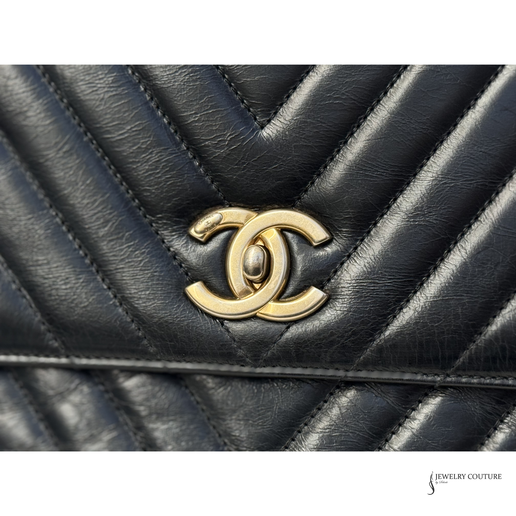 Close-up of a black quilted handbag with a gold Chanel logo.