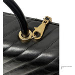 Black quilted handbag with gold handle and clasp on a white background