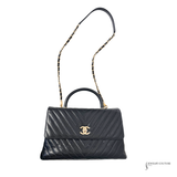 Black quilted handbag with gold chain strap on a white background
