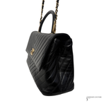 Black quilted handbag with gold chain strap on a white background