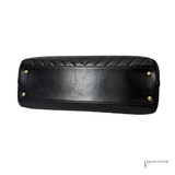 Black quilted handbag with gold studs on a white background