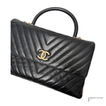 Black quilted handbag with gold logo on a white background