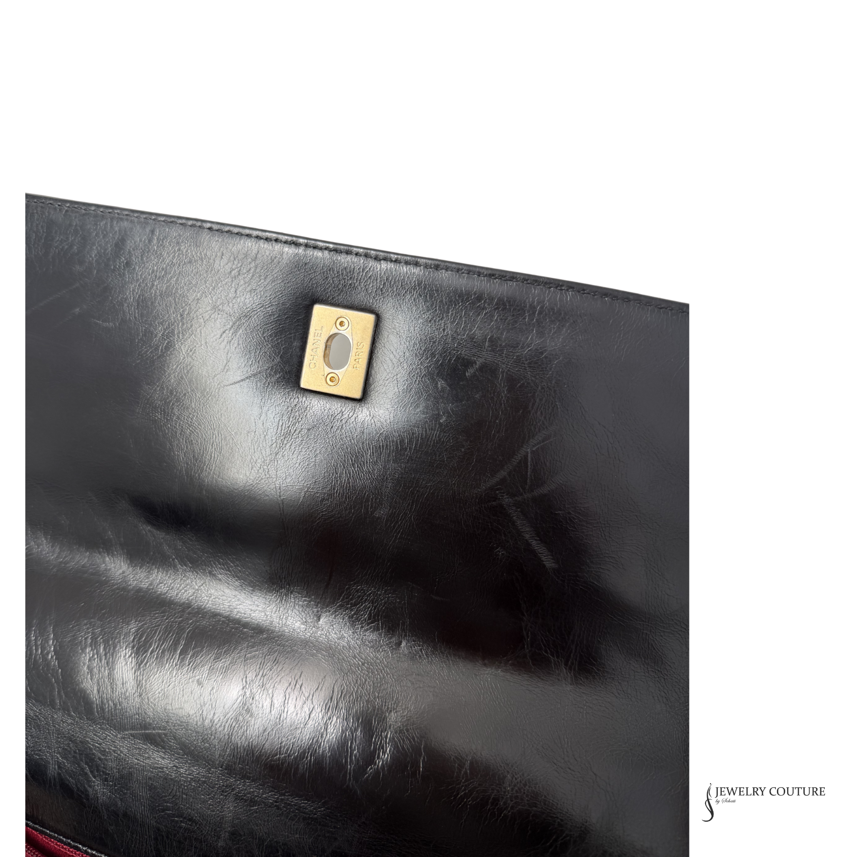Close-up of a black leather clutch with a gold clasp on a white background.