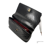 Black leather clutch bag with gold accents on a white background