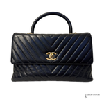 Navy blue quilted handbag with gold Chanel logo on a white background