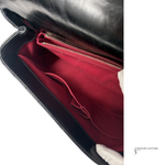 Black handbag with red interior lining, featuring a visible brand name.