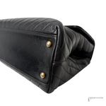Black quilted handbag with gold studs on a white background