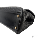 Black quilted handbag with gold studs on a white background