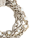 A close-up of a multi-strand bracelet featuring silver-tone chain links, braided chain, and white pearl beads on a plain white background.