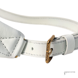 Close-up of a white leather bracelet with a gold tag on a white background
