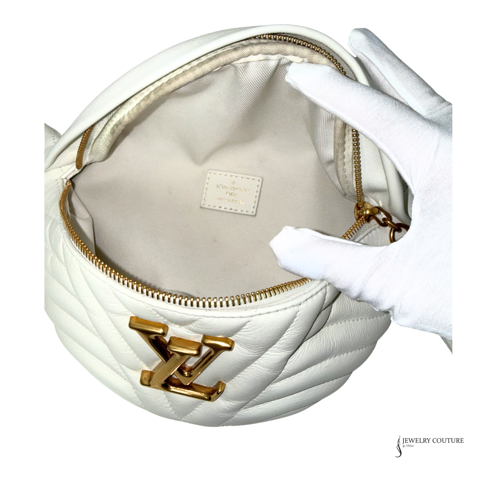 White handbag with gold chain and logo, held by a gloved hand on a white background.