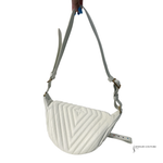 White quilted crossbody bag held by a hand on a white background
