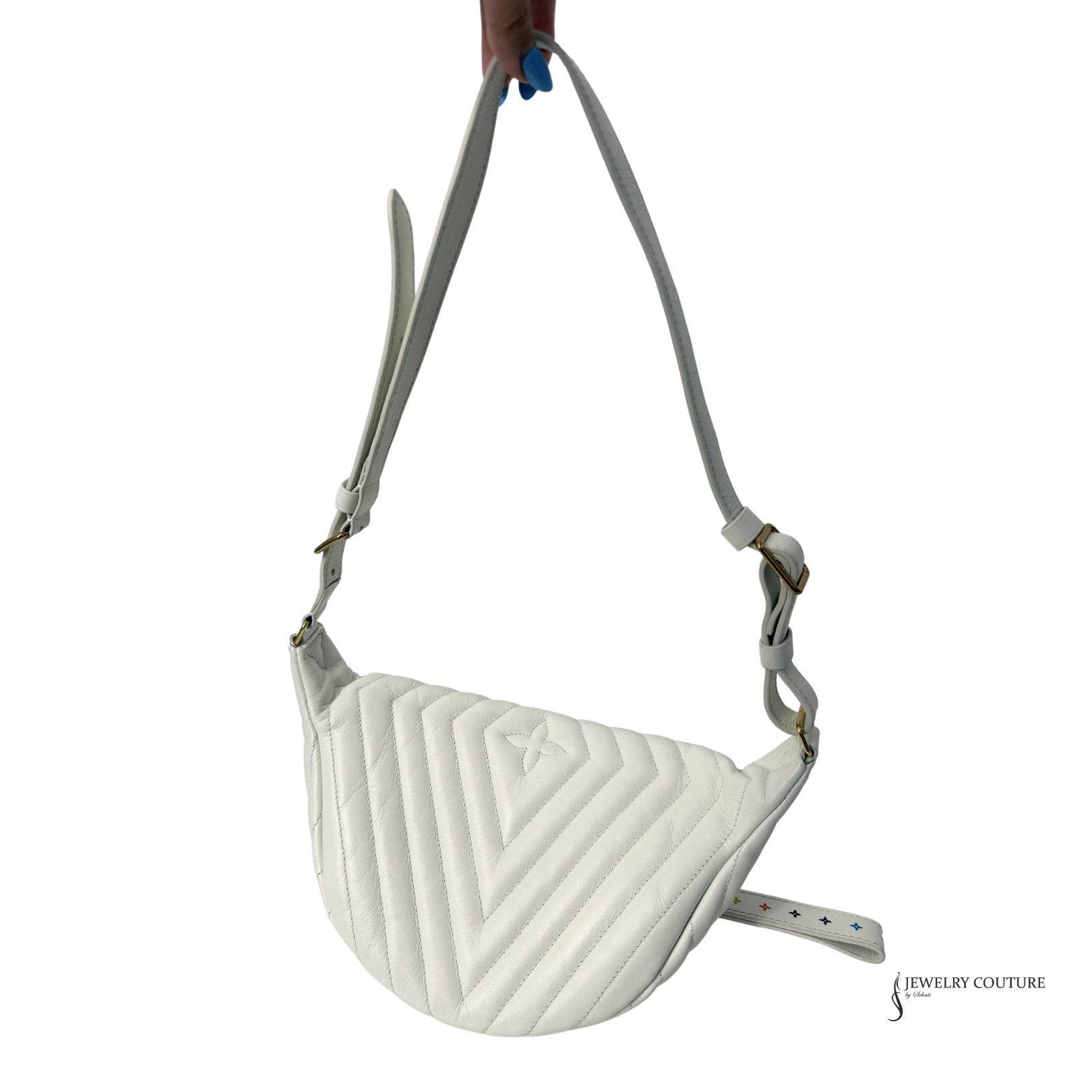 White quilted crossbody bag held by a hand on a white background