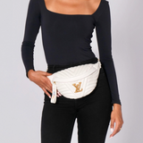 Person wearing a white quilted fanny pack with a brand logo on a plain background