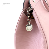 Pink handbag with a silver Louis Vuitton keychain on a white background