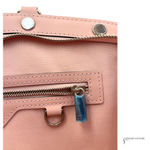 Close-up of a pink handbag with a blue tag and 'Jewelry Couture' branding.