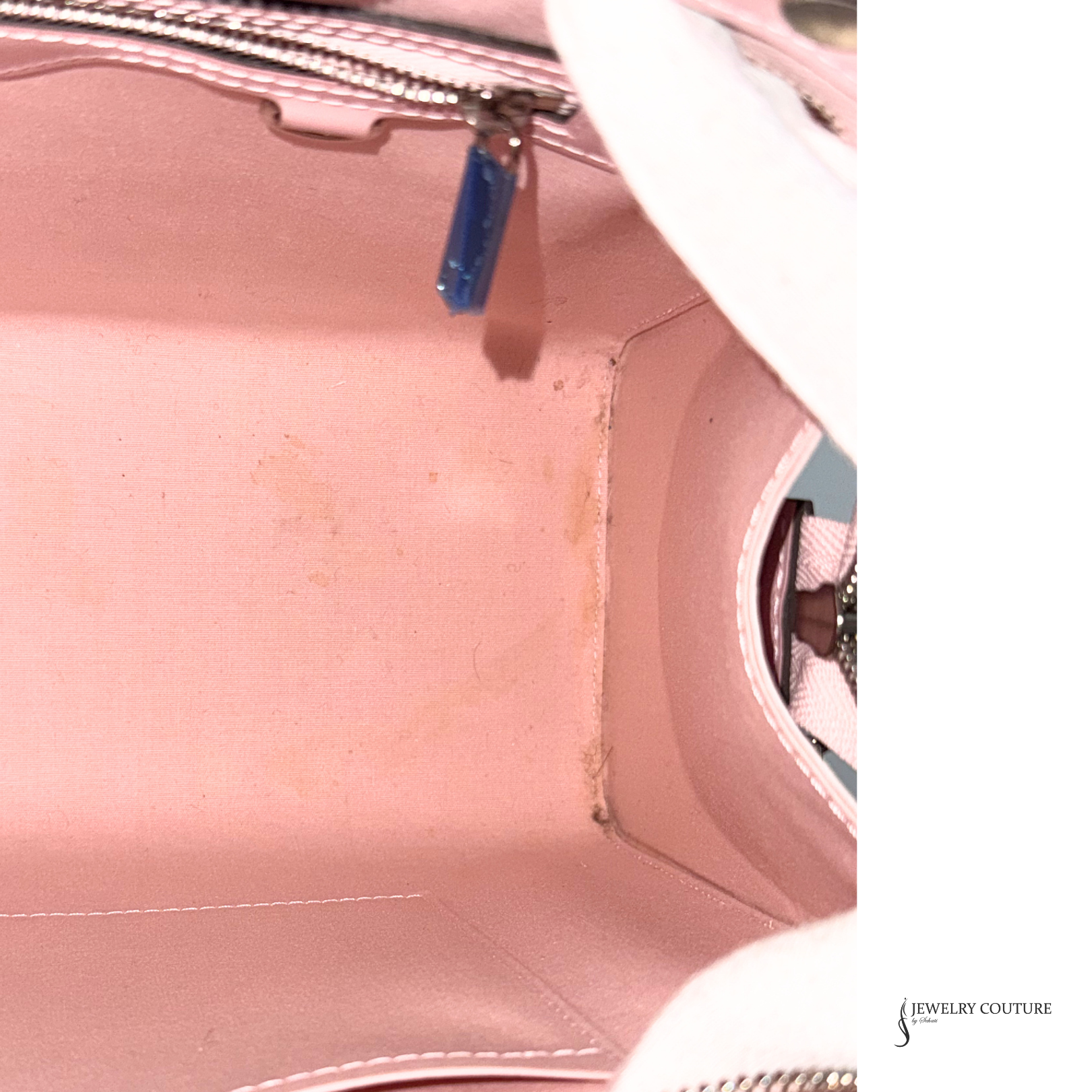 Close-up of a pink handbag with visible wear and tear on a white background.