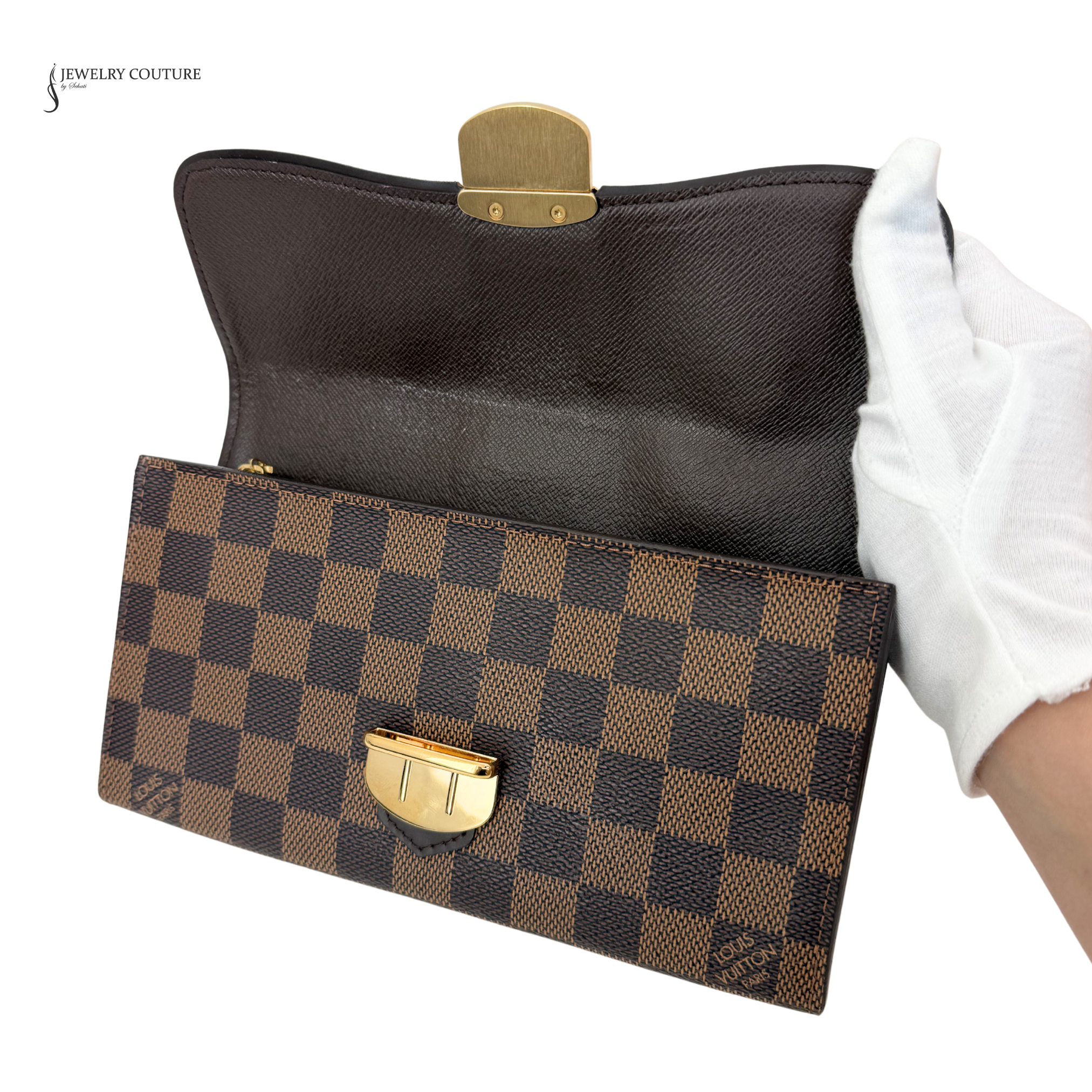 Brown checkered clutch bag with gold clasp held by a gloved hand on a white background