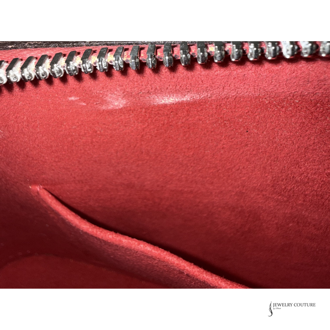 Close-up of a red leather clutch with a zipper, brand 'Jewelry Couture' visible.