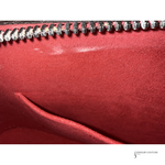 Close-up of a red leather clutch with a zipper, brand 'Jewelry Couture' visible.