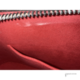 Close-up of a red leather clutch with a zipper, brand 'Jewelry Couture' visible.