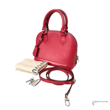 Red handbag with matching strap, keychain, and dust bag on a white background