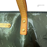 Green handbag with brown leather handle and visible brand logo